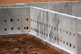 Poured foundation showing fourm ties coated with roofing cement