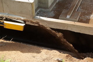 A picture of rock being put around a foundation drain